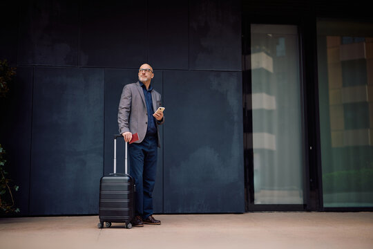 Full length of businessman with travel bag and passport on airport terminal.