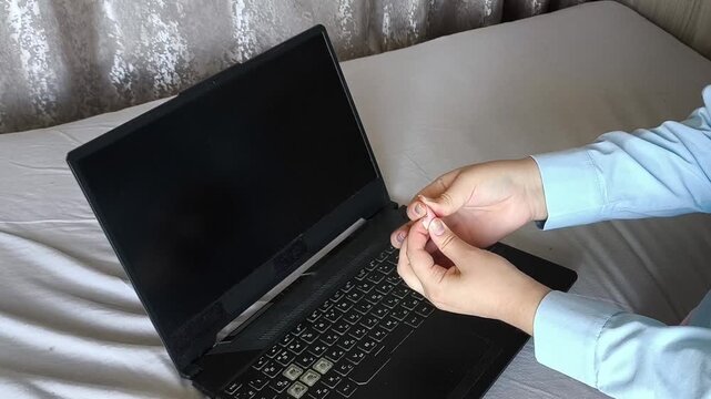 Woman covering the laptop webcam with modeling clay, symbolizing webcam privacy, cybersecurity, protection from online surveillance and unauthorized camera access