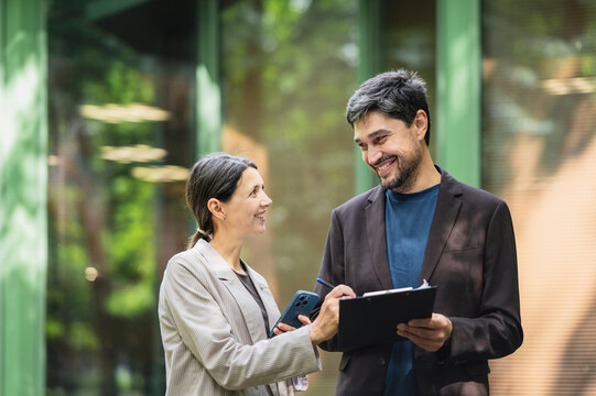 Smiling businessman and businesswoman discuss a contract outdoors