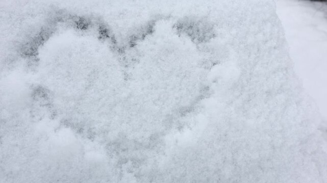 Snow heart shape drawn on a winter day in a snowy outdoor area