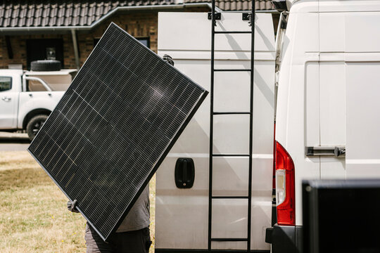 Worker carries solar panel for photovoltaic installation outdoors