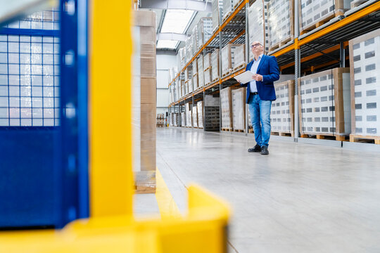 A manager checks inventory on a tablet in a large warehouse