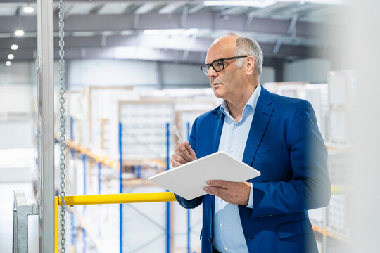 A businessman checks inventory with a tablet in a warehouse