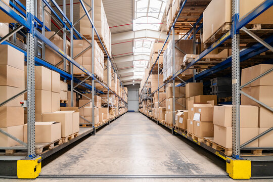 Empty warehouse aisle stores cardboard boxes on metal shelves
