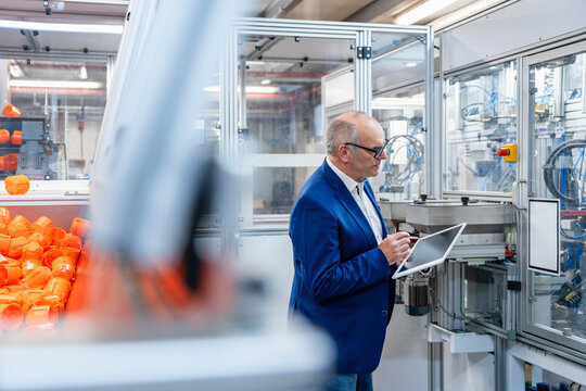 Male manager checks tablet in modern production hall