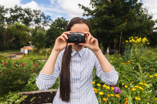 Young woman takes a photo with a camera in a summer garden