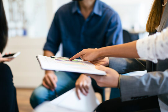 Hand pointing on chart on clipboard in a business meeting