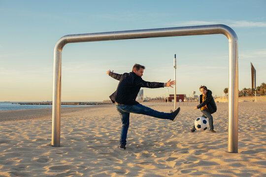 Father and son playing football on the beach