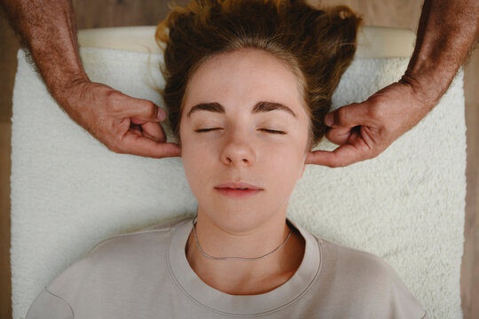 Osteopath massaging head of woman with eyes closed