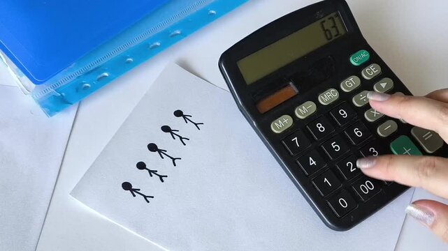 Close up of a drawing representing groups of people next to a woman using a calculator, illustrating demographics, population statistics, birth rates, data analysis and population research.