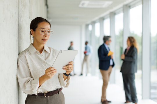Businesswoman uses digital tablet in modern office corridor