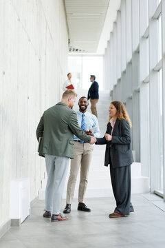 Businessman and businesswoman shake hands in a modern office hallway