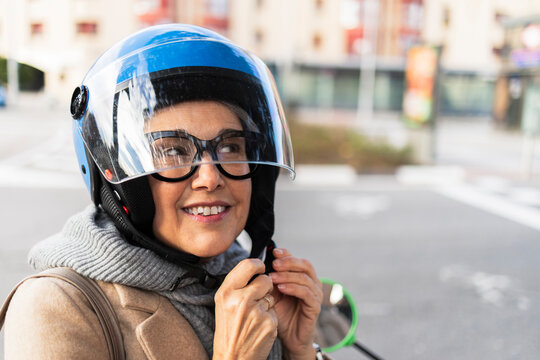 Confident woman fastening helmet outdoors ready for urban commute