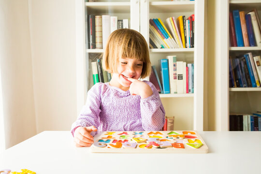 Portrait of smiling little girl learning alphabet with wooden letters