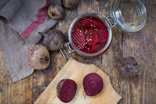 Preserving jar of pickled beetroots and whole and sliced beetroots on wood