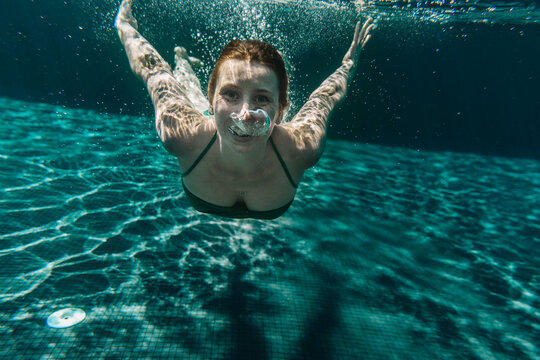Portrait of happy woman diving in a swimming pool