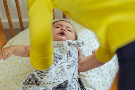 Mother picking up her baby girl from bed
