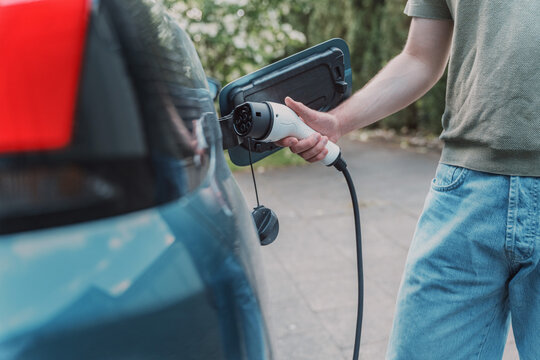 Man charging his blue electric vehicle at home in Germany
