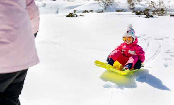 Girl sitting on sledge, mother pulling