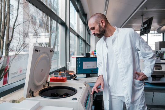 Male scientist operates a centrifuge in a high tech laboratory