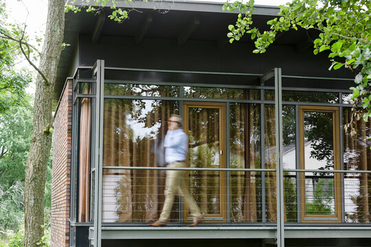 Man on the phone walking on balcony of his house