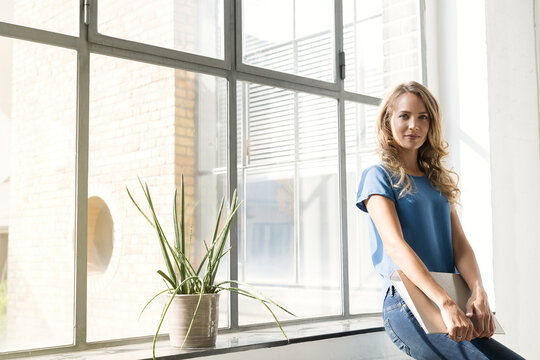 Casual businesswoman in office holding folder