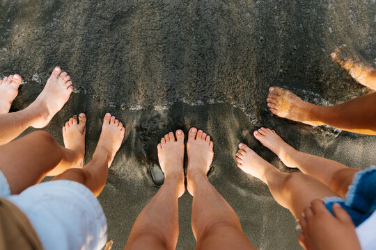 A family touches the ocean water with their bare feet