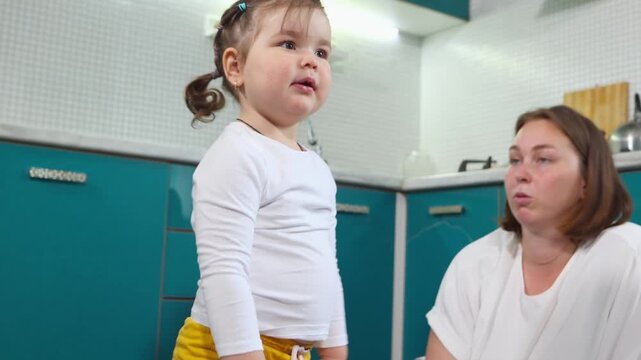 Young Caucasian woman helps a little girl practice mopping in a kindergarten classroom. The practical Montessori lesson encourages independence, concentration, coordination, and responsibility.