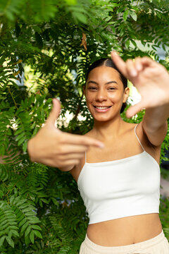 Happy woman makes a framing gesture with her hand outdoors