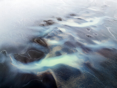 Glacial water weaves through volcanic sediment in Iceland estuary