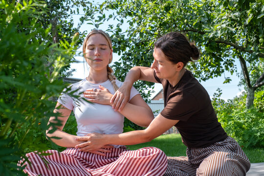 An instructor guides a woman through somatic therapy in a garden