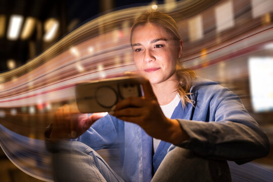 Woman uses mobile device with colorful AI chatbot composing at night
