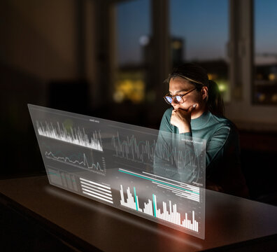 Businesswoman analyzes data on a futuristic hologram screen at night