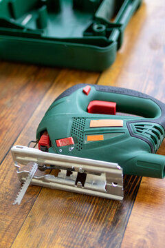 Electric jigsaw rests ready on outdoor table before cutting pine board for DIY shelf project. Concept of tool readiness and organized workspace setup in home woodworking preparation process.