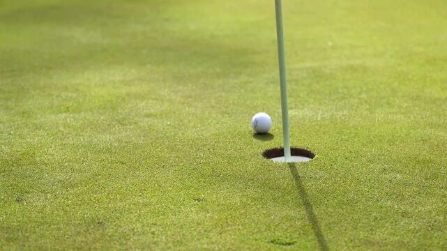 A golf ball spinning and just missing the hole.