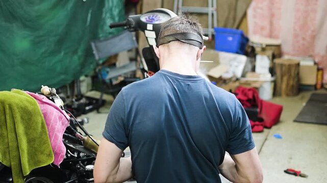 Skilled Mechanic Repairing Scooter Engine in a Cluttered Garage Workshop