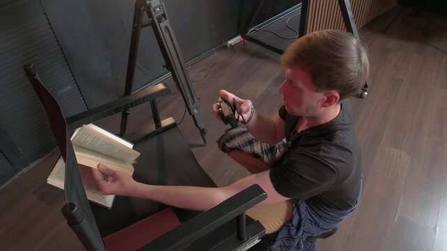 Young Man Kneeling and Photographing Pages of an Open Book in a Studio
