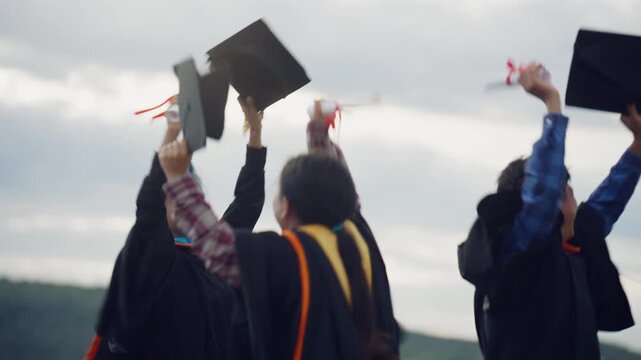University Graduates Raising Caps and Diplomas to Celebrate Graduation