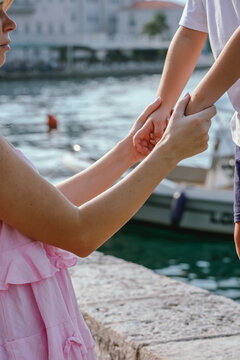 Close-up of mother holding child's hands by waterfront