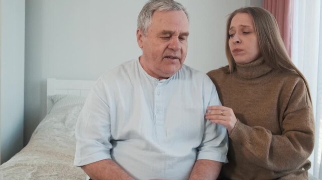 Loving adult daughter comforts and hugs her upset senior father while sitting together at home. Family love, emotional support, care, empathy, close relationships, parent support and family bonds