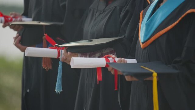 Graduates Holding Diplomas and Academic Caps Together at Graduation Ceremony
