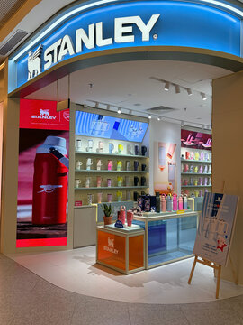 A retail store featuring Stanley branded products. It showcases various colorful drinkware and accessories on shelves. The storefront is brightly lit and modern.