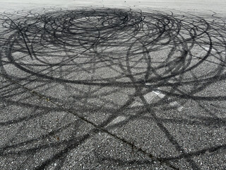 Black tire marks swirl across asphalt surface © schankz