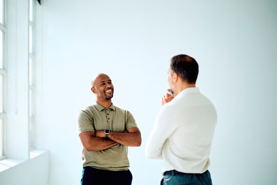 Two diverse business men standing, smiling, and having a conversation. Showing successful communication and teamwork
