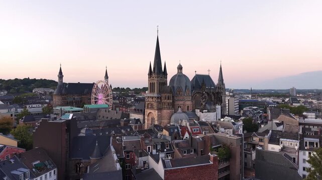 Anflug einer Drohne auf das historische Zentrum von Aachen mit Aachener Dom, Rathaus und Riesenrad bei D&auml;mmerung
