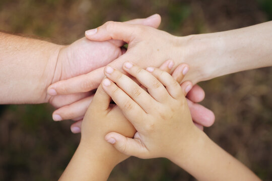 Adult and child hands stacked together outdoors