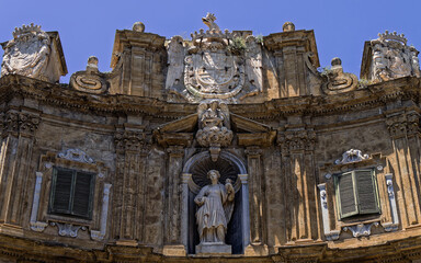 A detailed close-up capturing the late Renaissance sculpture of Saint Agatha nestled in a decorative niche at Palermo's Quattro Canti, framed by ornate stone cornices and historic heraldry. © Dimitrios