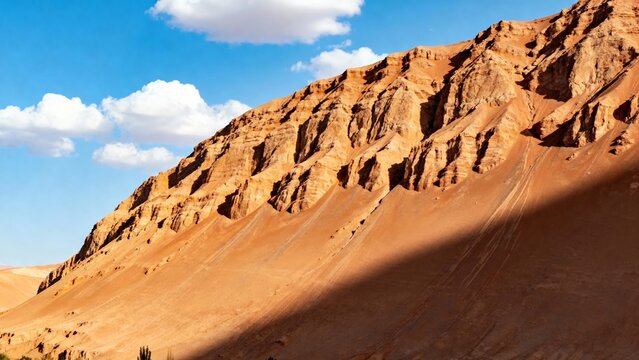 Rugged red rock formations and sand dunes under a clear blue sky in a desert landscape