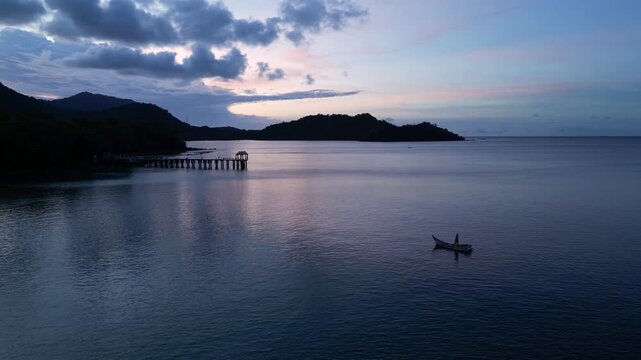 Weh Island, Indonesia : Aerial drone footage above traditional boat heading to Gapang beach in Pulau Weh in Sabang in Aceh province in Sumatra, Indonesia with jetty under dramatic sunset sky
