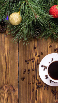 Christmas holiday decor composition with pine branches, shiny ornaments, natural pine cones, steaming coffee cup, scattered coffee beans on rustic wooden surface, vertical photo